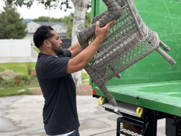 junk movers expert loading old chair into back of truck during junk removal services